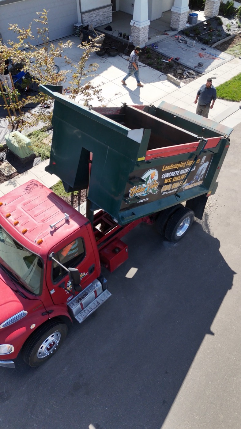 Golden Valley Materials truck lifting its bed to unload material in a residential driveway