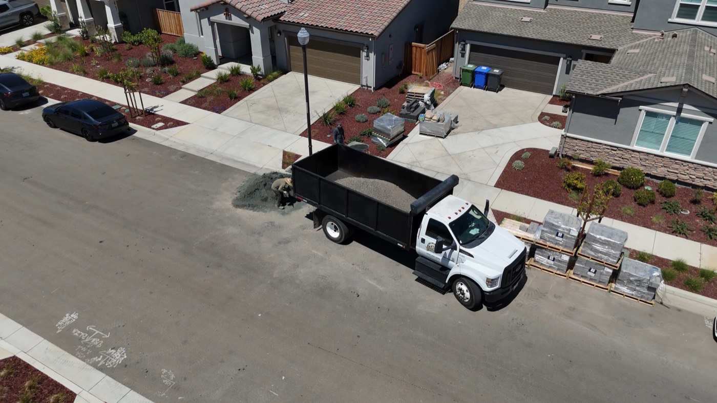 Delivery truck and pallets of pavers staged at a residential home