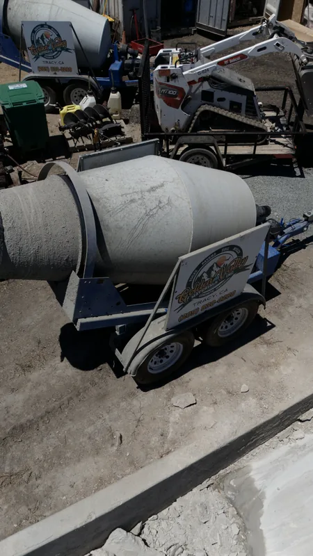 Our Golden Valley concrete mixer trailer alongside a Bobcat mini track loader and augers — rental gear ready to go.