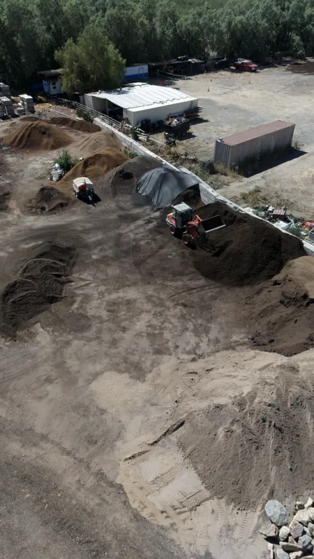 Aerial view of our topsoil and soil-blend piles, with a loader on hand to fill orders fast for pickup or delivery.