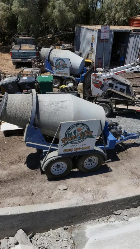 Our Golden Valley Materials concrete mixer trailer parked at the yard, with a mini track loader behind it.